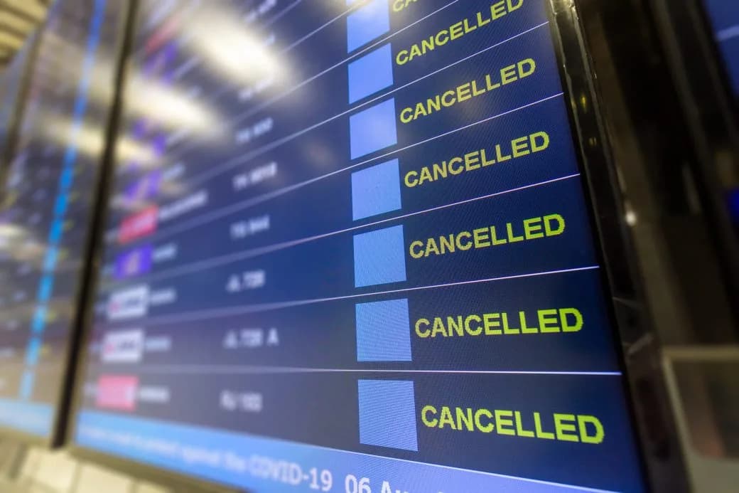 An airport departure board showing a row of flights marked cancelled.