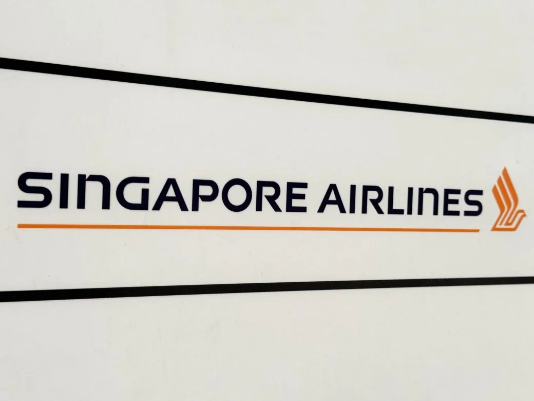 A Singapore Airlines sign with the airline's name and logo on a white panel.