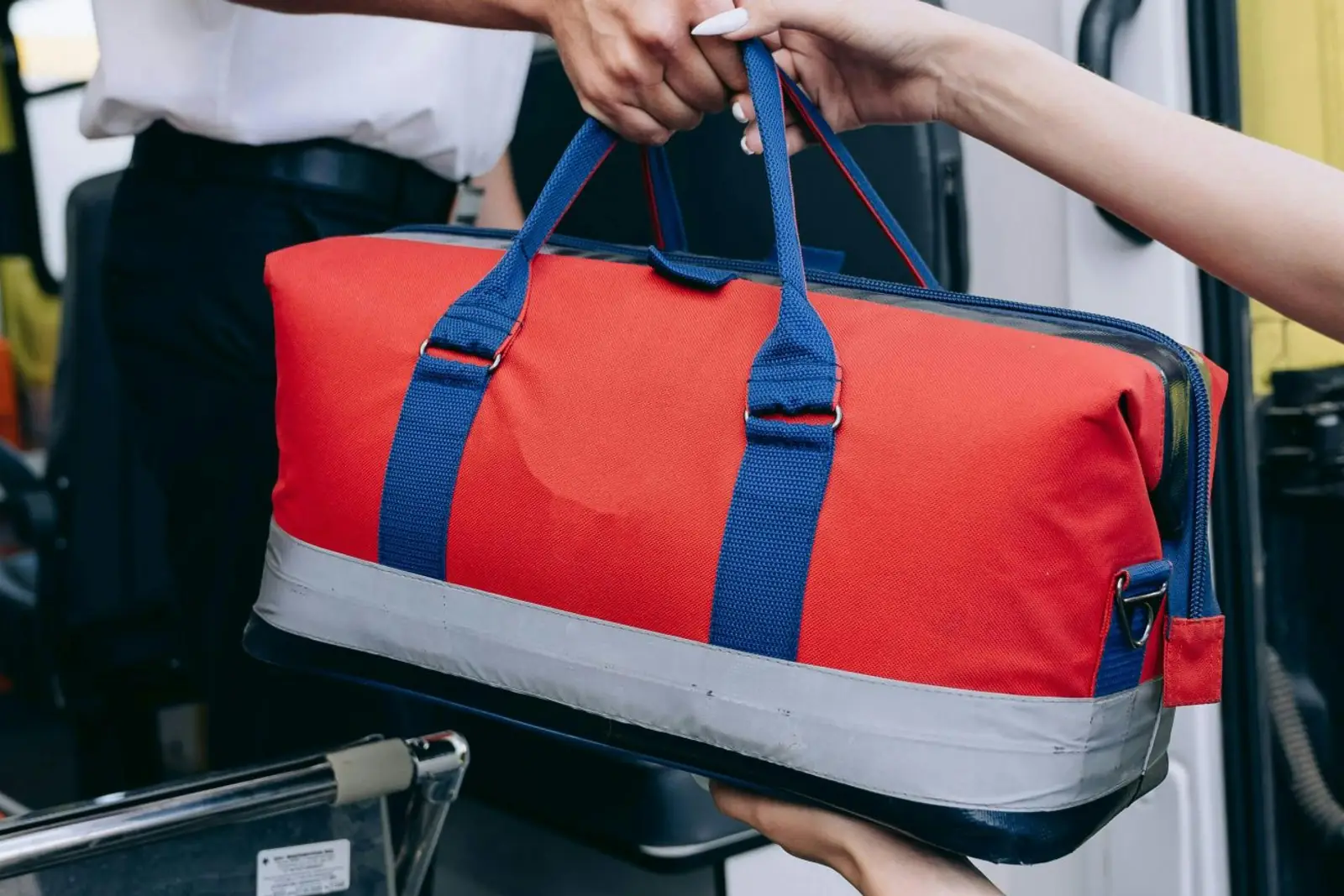 A paramedic's red medical bag handed over at the open doors of an ambulance.