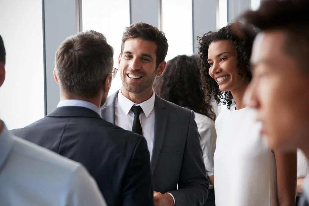 A group of business professionals smiling and chatting at a networking event.