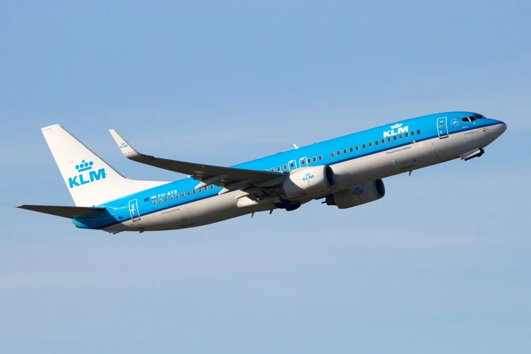 A KLM aircraft climbing after take-off against a blue sky.