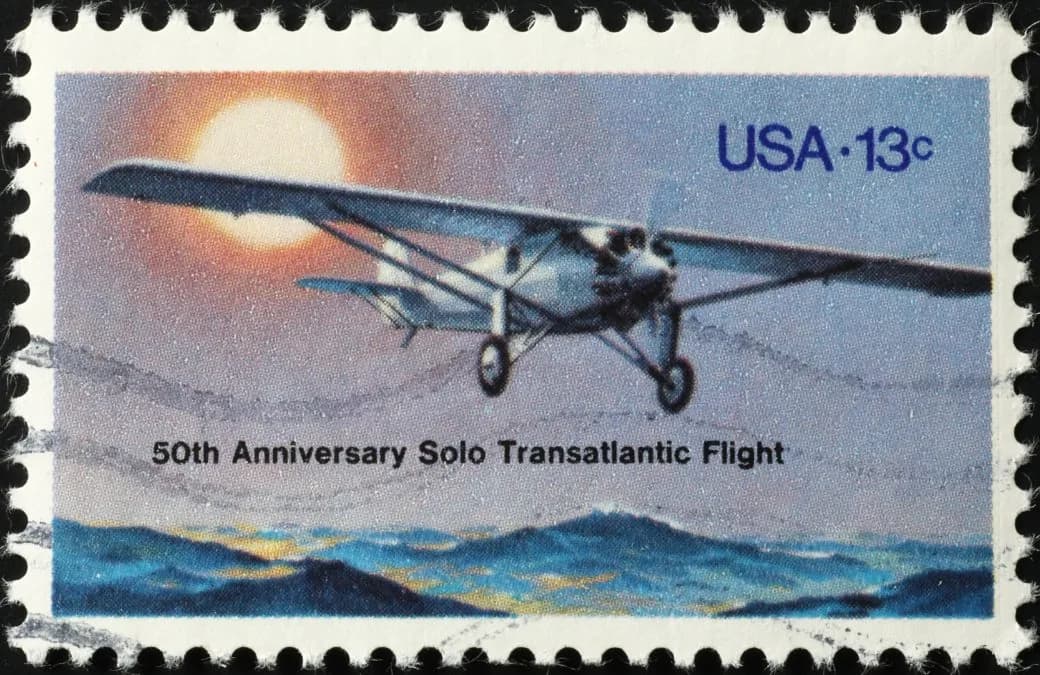 A postage stamp marking the 50th anniversary of the solo transatlantic flight, showing a small aircraft at sunset.